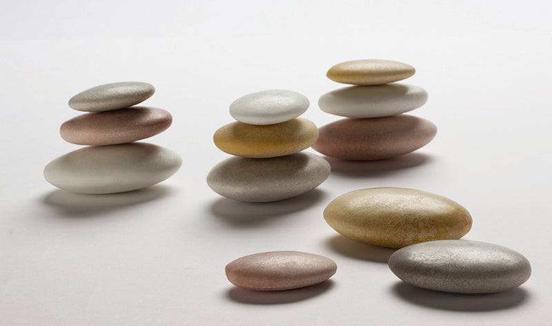 Smooth, multi-colored natural sorting stones stacked and scattered on a clean white background.