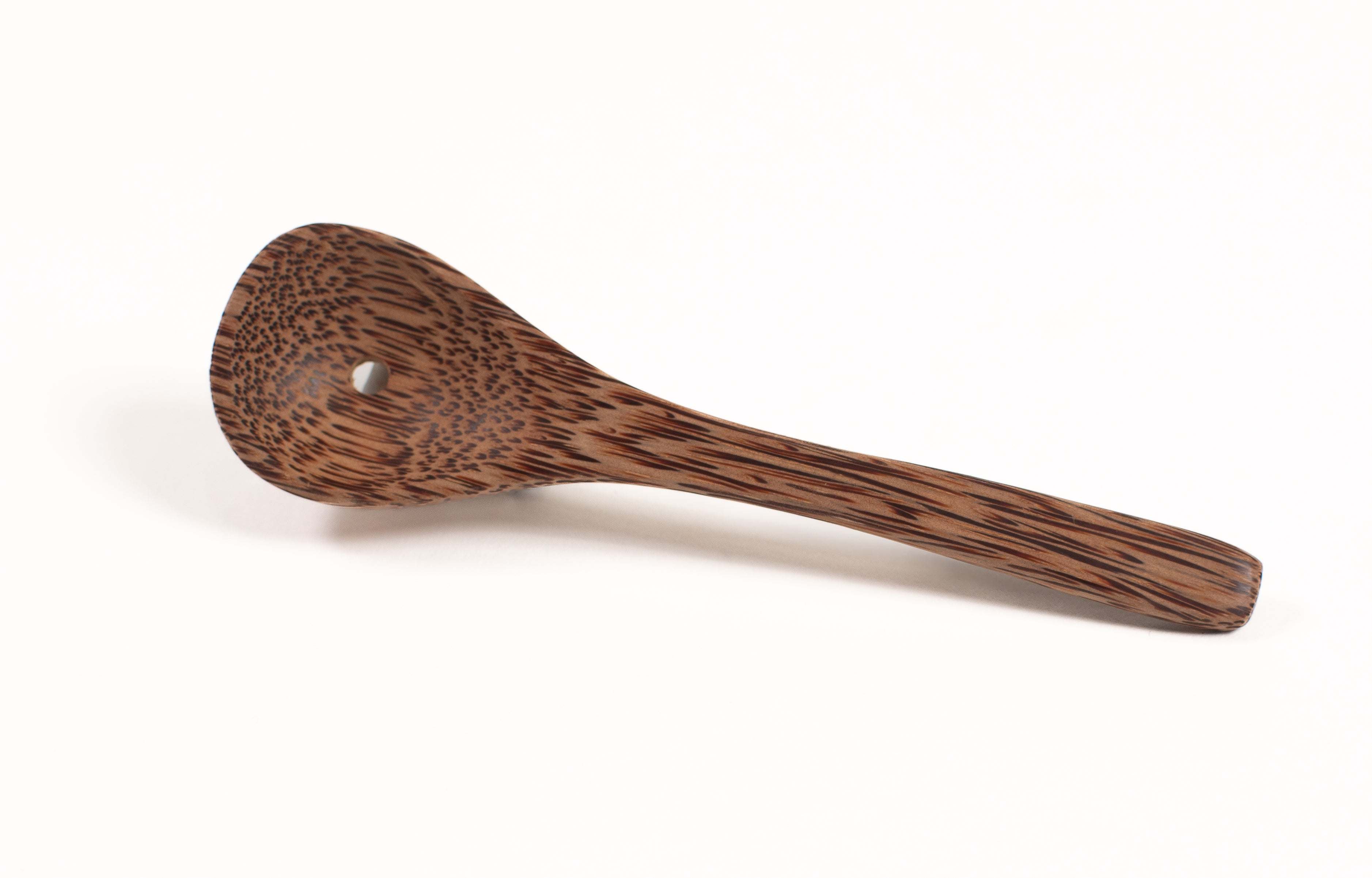 Small brown spoon made from natural coconut shell with a smooth, wood-grain texture and a single hole in the bowl.