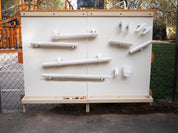 Outdoor STEM magnet wall with white metal panels, magnetic ramps, and storage trays for interactive playground learning.
