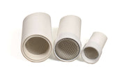 Set of three white cylindrical outdoor sifter scoops with metal mesh screens for sensory play in sand and dirt.
