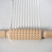 Wooden patterned rolling pins creating designs on clay surface