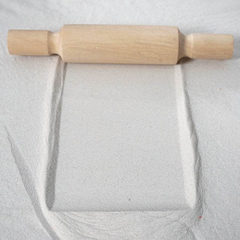 Wooden patterned rolling pins creating textured designs on clay and sand surfaces