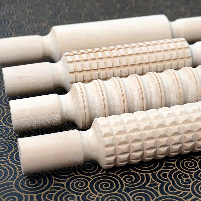 Wooden patterned rolling pins creating textured designs on clay surface
