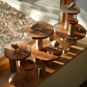 Handmade wooden pebble animals and tiered mushroom-shaped platforms on a sunny windowsill.