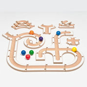 Modular wooden puzzle ball track with white and natural wood finish, featuring colorful spheres and various curved path segments.