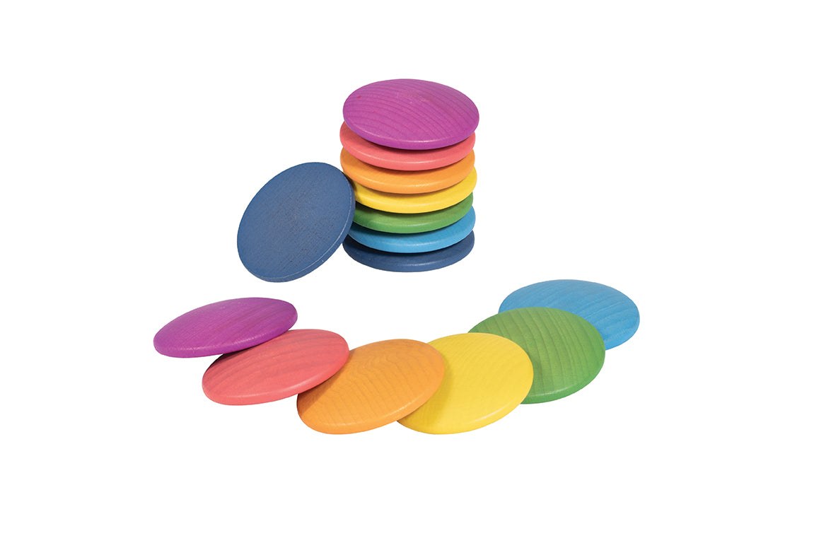 Stack of smooth, colorful wooden discs in rainbow shades arranged on a white background for open-ended play.