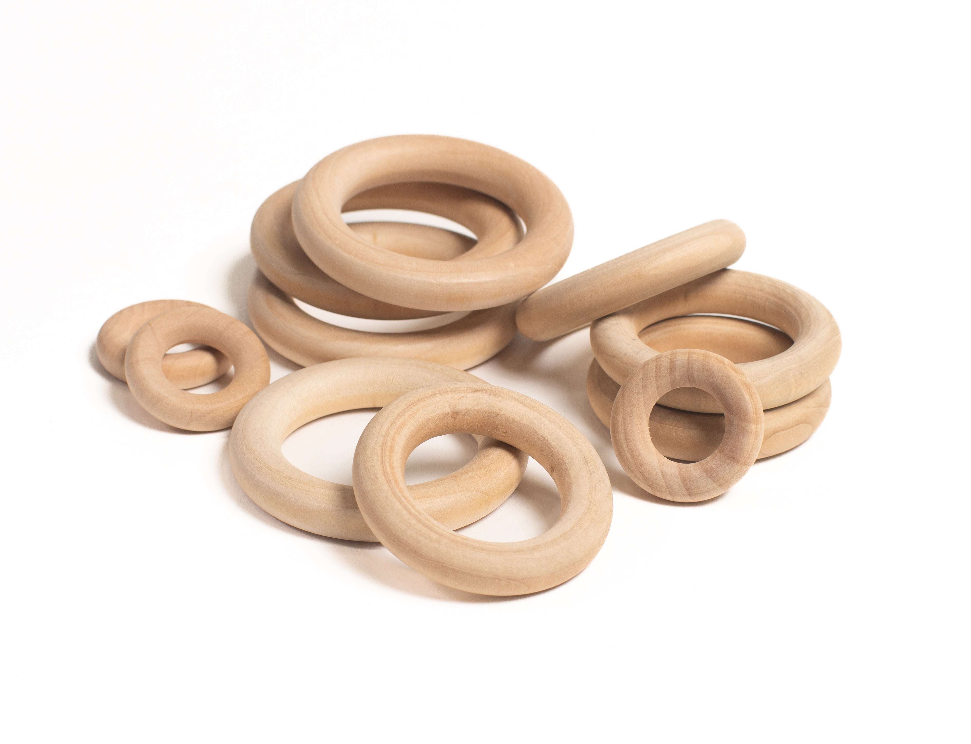 A pile of smooth, natural wooden rings in three different sizes for sensory play and STEM learning.