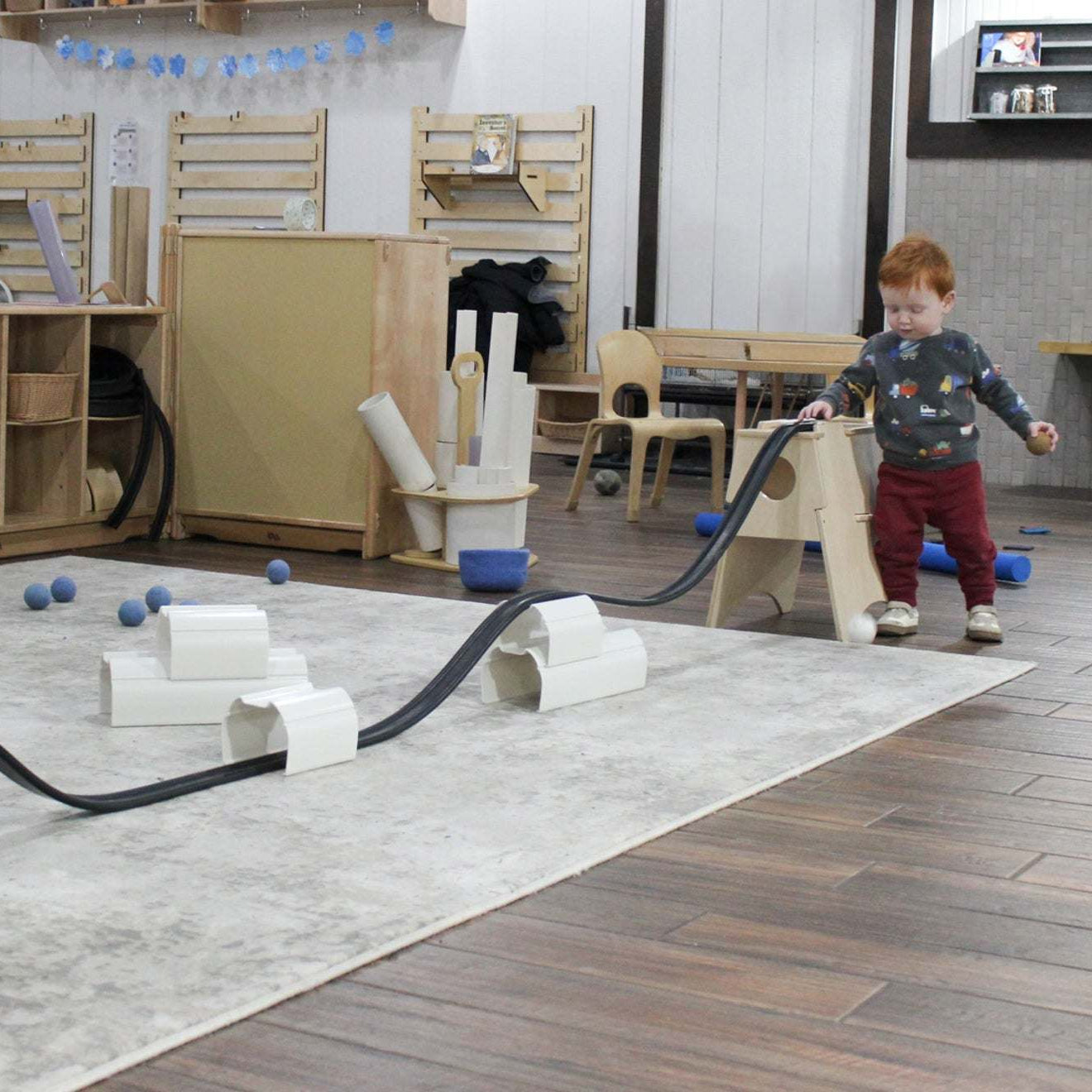Children playing with a 25-foot flexible rubber ramp and stackable stands for STEM learning