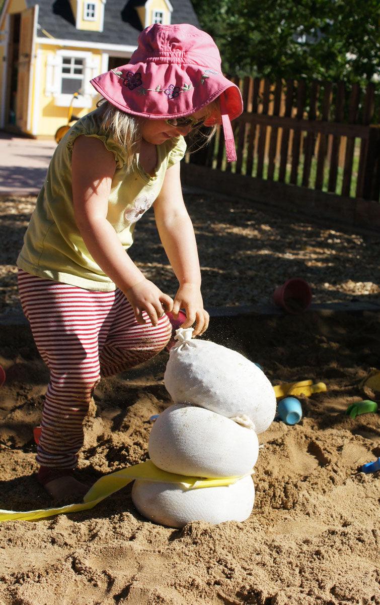 Children playing and building with flexible white sandbags in a classroom setting