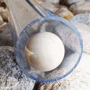 A smooth wooden ball rolls through a clear, durable plastic pipe resting on a bed of grey river stones.