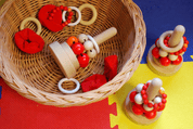 Woven wicker basket containing red and white wooden bead toys and rings on a colorful foam play mat.
