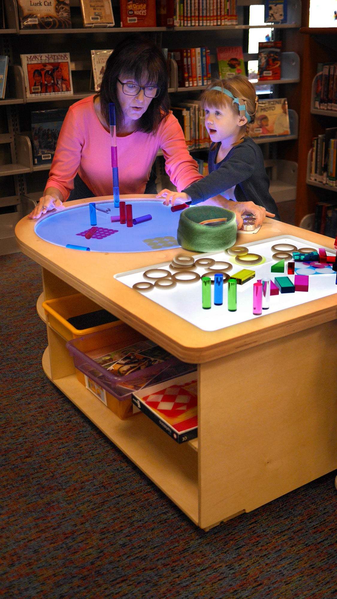 Teacher and child exploring a wooden Spectrum Light Lab table with circular and rectangular illuminated panels.