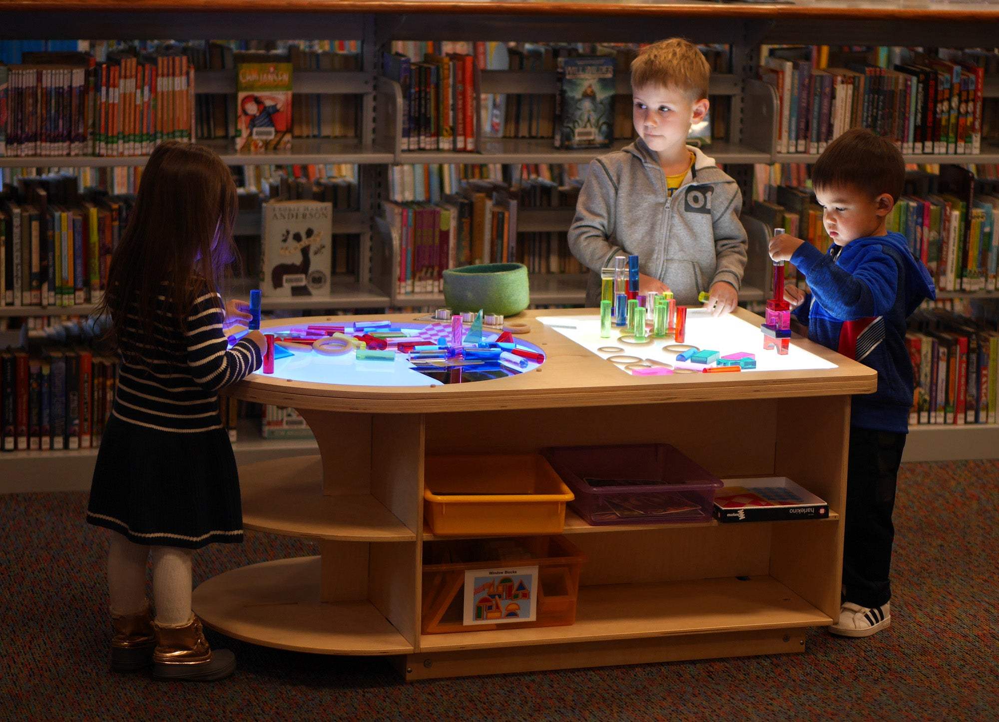 Children playing with colorful blocks on a wooden Spectrum Light Lab table with built-in storage in a library.