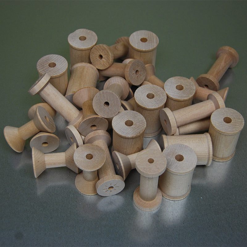 A pile of natural light-colored wooden spools of varying sizes for open-ended STEM play and creative building.