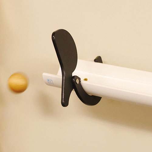 Black plastic stop and go gate clipped onto a white Kodo ramp with a wooden ball rolling nearby.