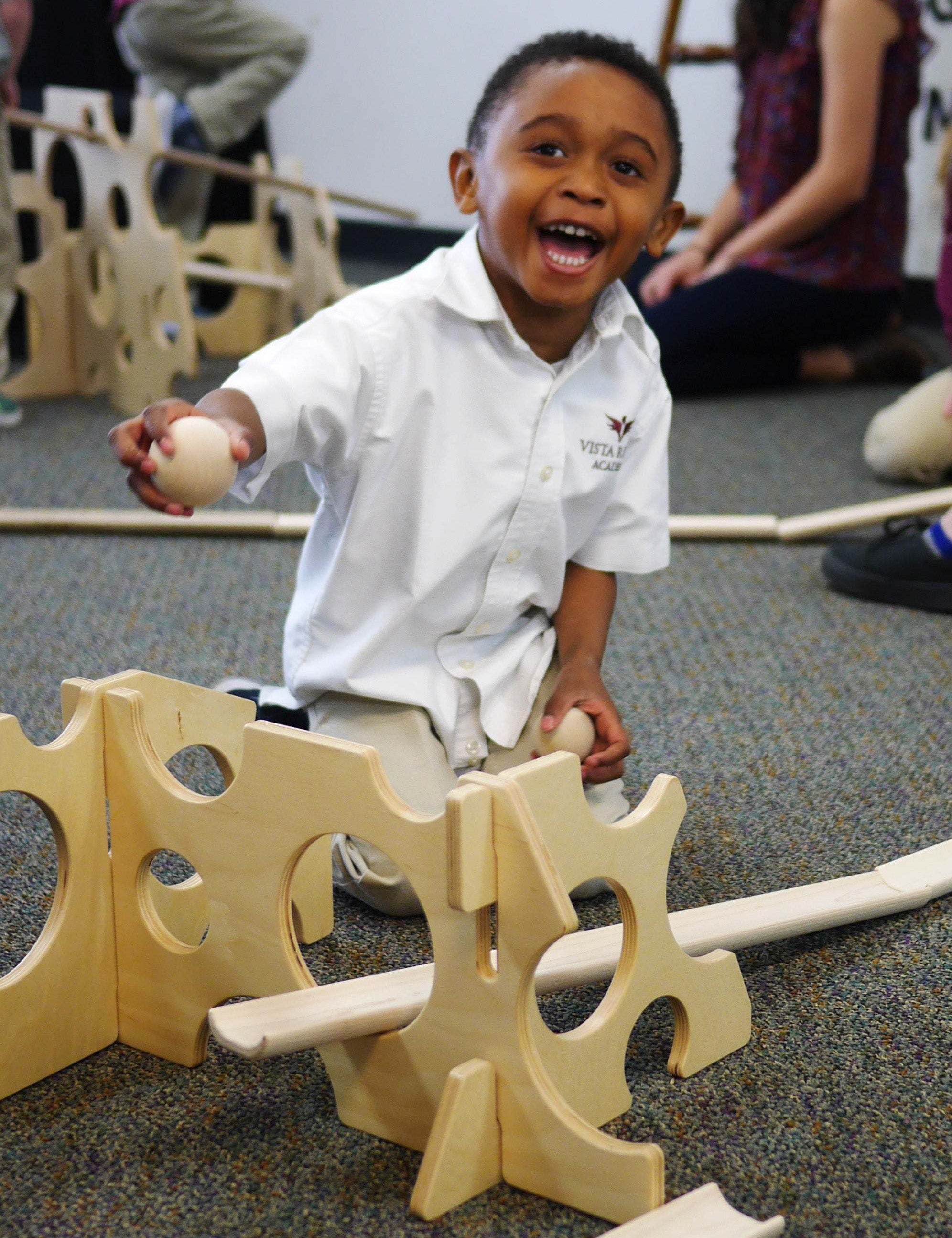 Child playing with light wood Swiss ramp stands featuring circular cutouts for STEM track building.