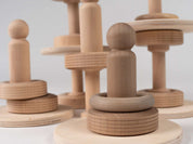 Natural wooden stacking toy set with smooth blocks, rings, and figures for toddler STEM play on a white background.