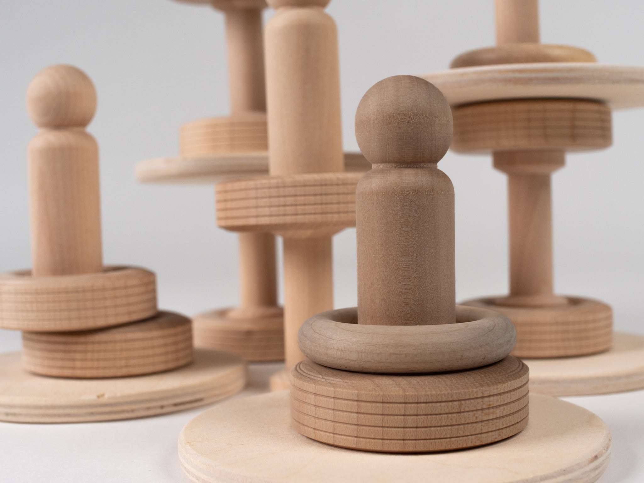 Natural wooden stacking toy set with smooth blocks, rings, and figures for toddler STEM play on a white background.