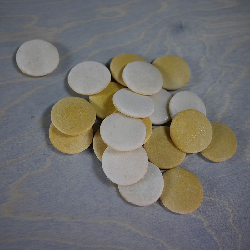Set of 20 smooth, round, two-tone white and yellow resin counting stones scattered on a wooden surface.