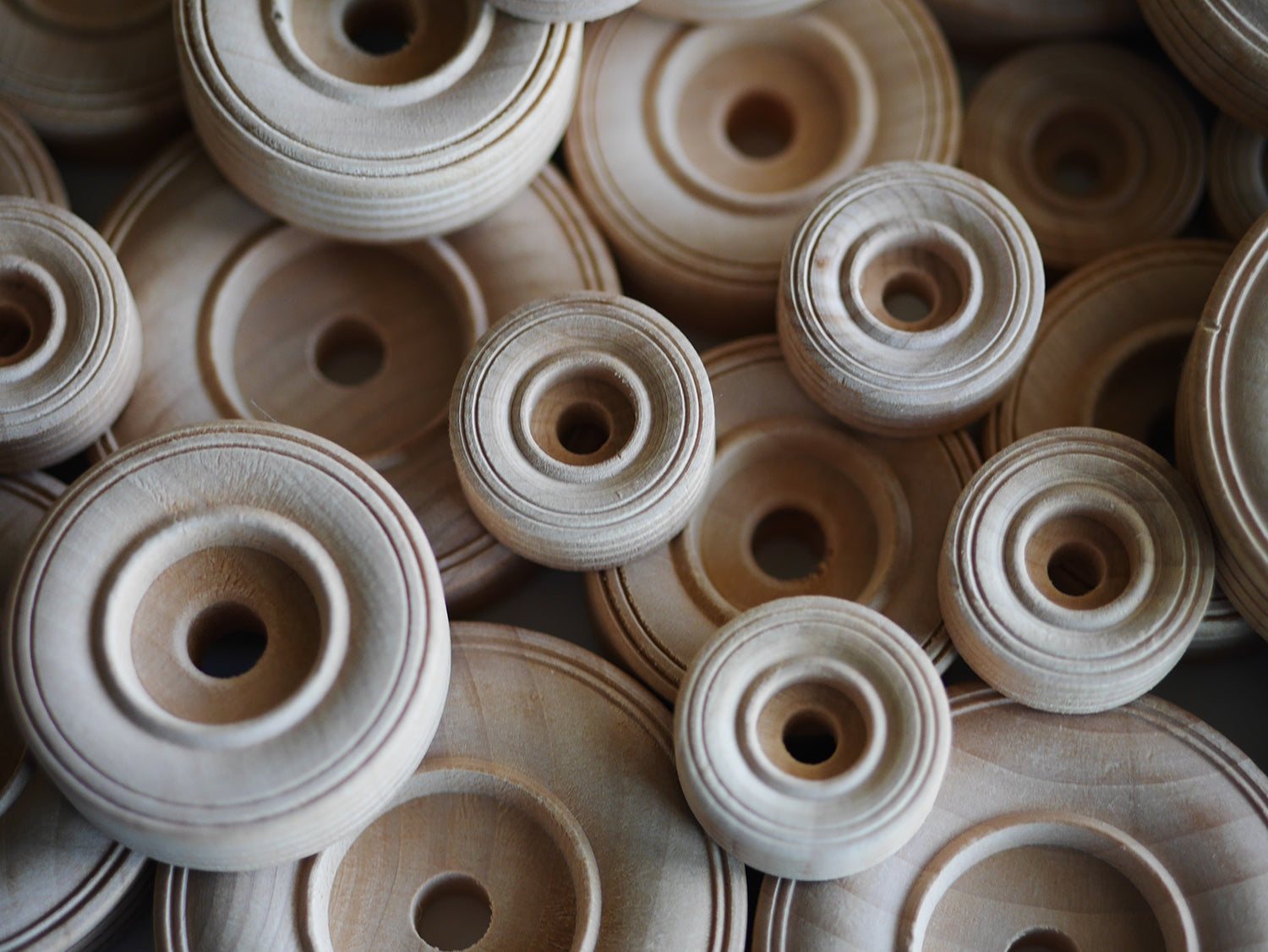 Assorted sizes of natural, unfinished wooden wheels with center holes for STEM engineering and loose parts play.