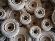 Assorted sizes of natural, unfinished wooden wheels with center holes for STEM engineering and loose parts play.