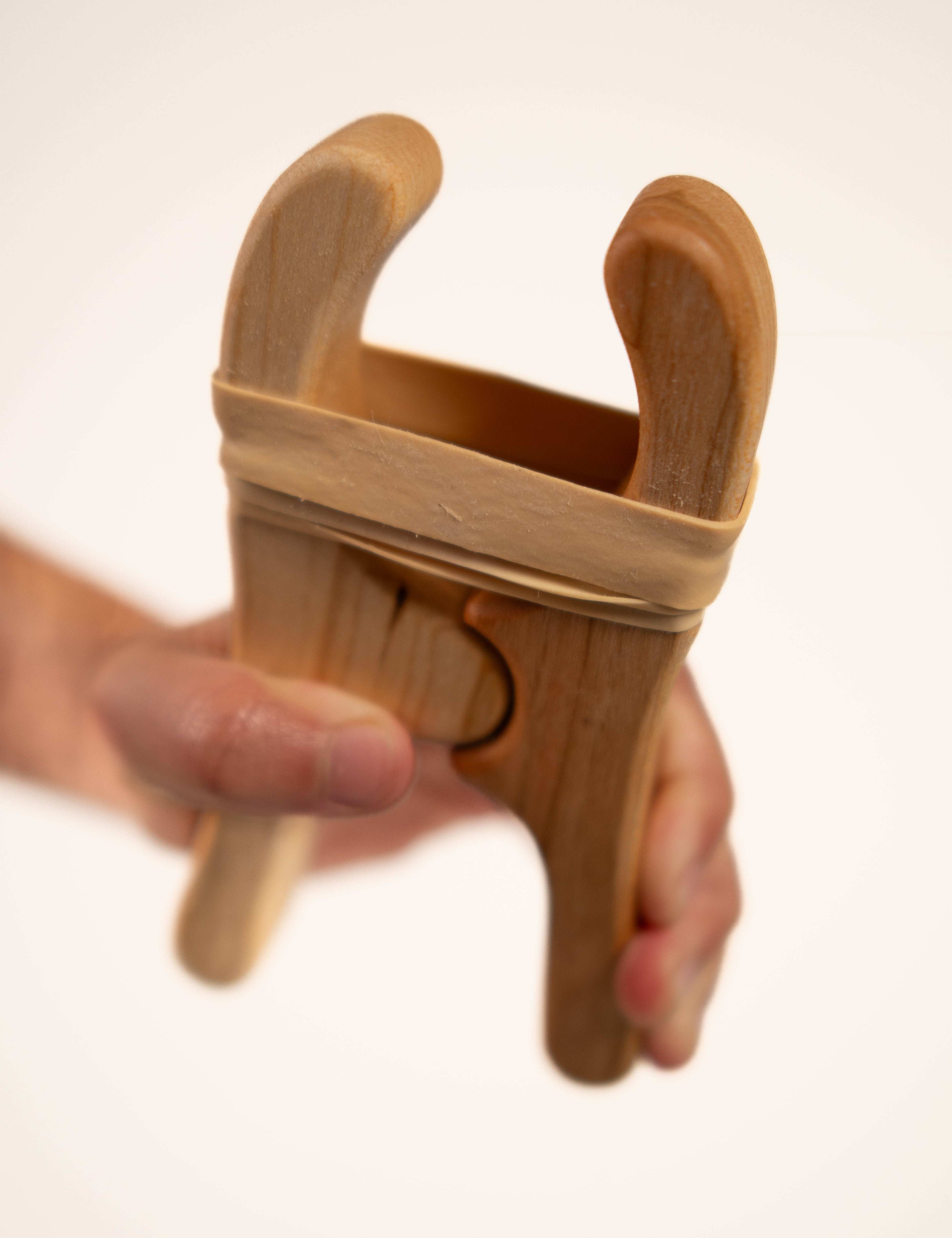Hand holding a smooth, beeswax-finished maple and cherry wood play clip with a sturdy rubber band for building forts.