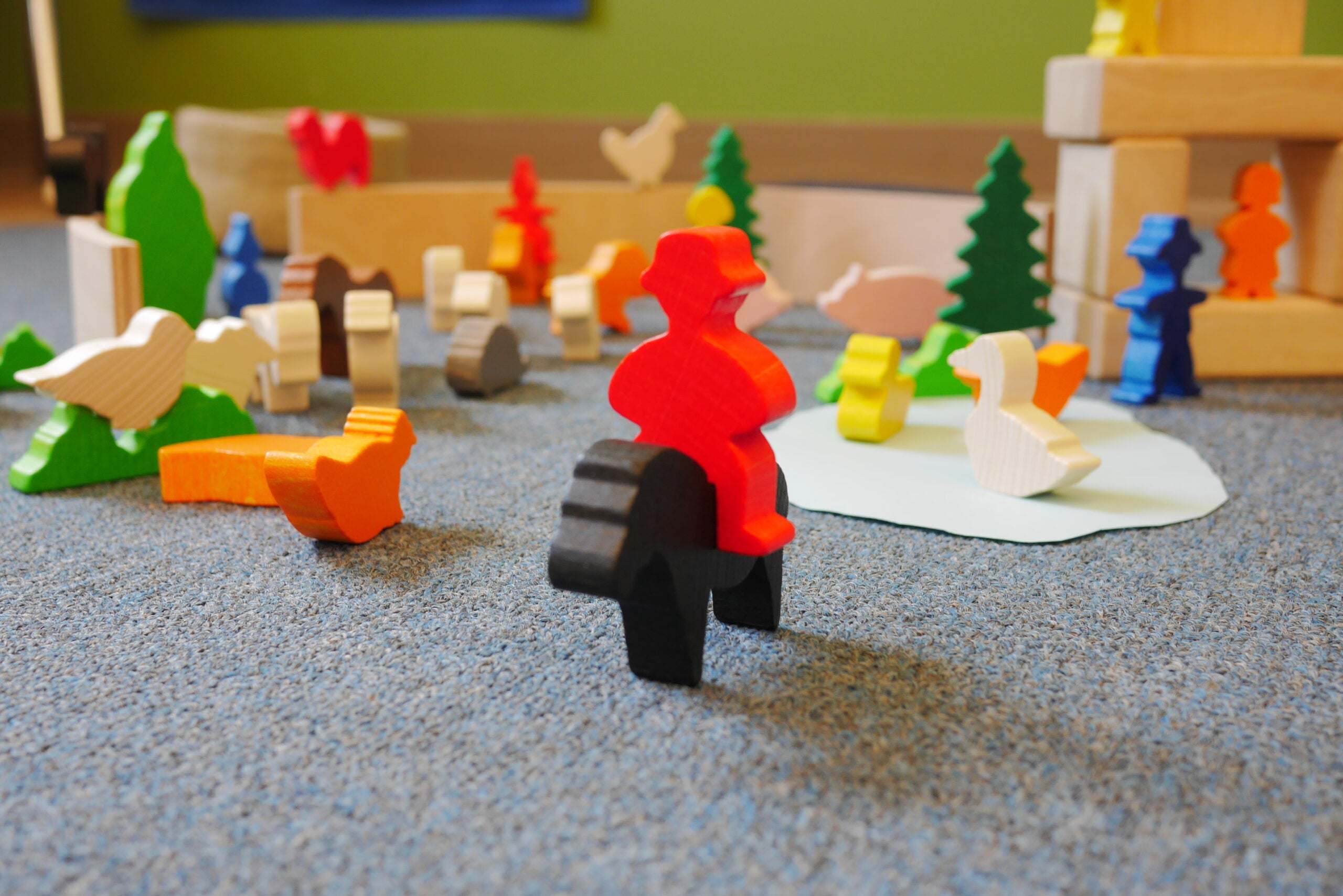 Set of 84 colorful hardwood farm animal and tree figures for educational play, featuring a red rider on a black horse.