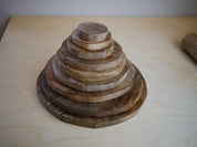 Stack of graduated natural wooden discs arranged by size on a light wooden surface.