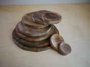 Stack of natural wooden discs in varying sizes, featuring a smooth, polished grain finish on a light wooden surface.