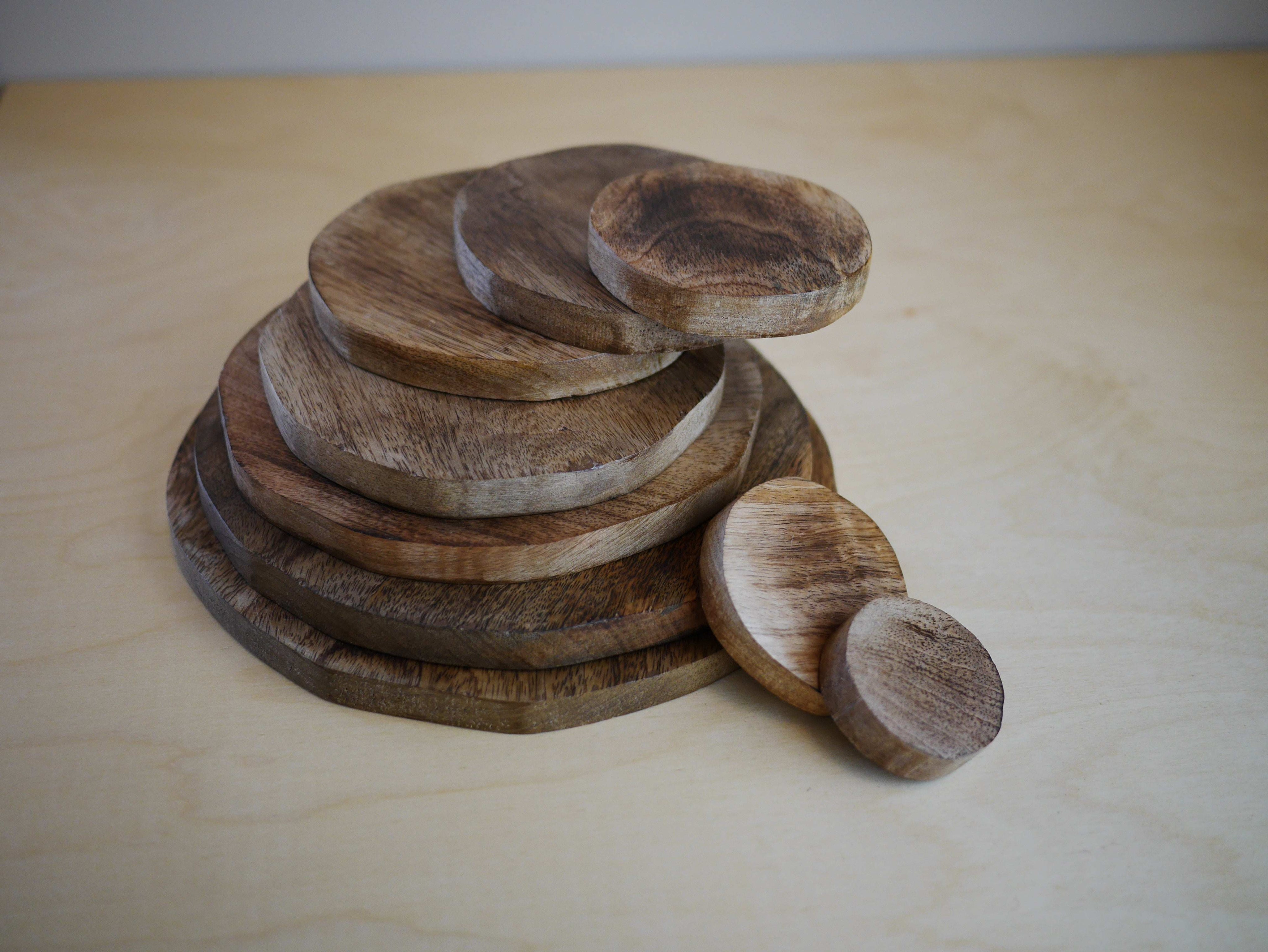 Stack of natural wooden discs in varying sizes, featuring a smooth, polished grain finish on a light wooden surface.