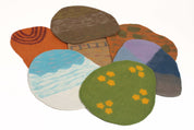 Colorful felted wool playscape mats with nature-inspired textures and patterns for sensory learning.