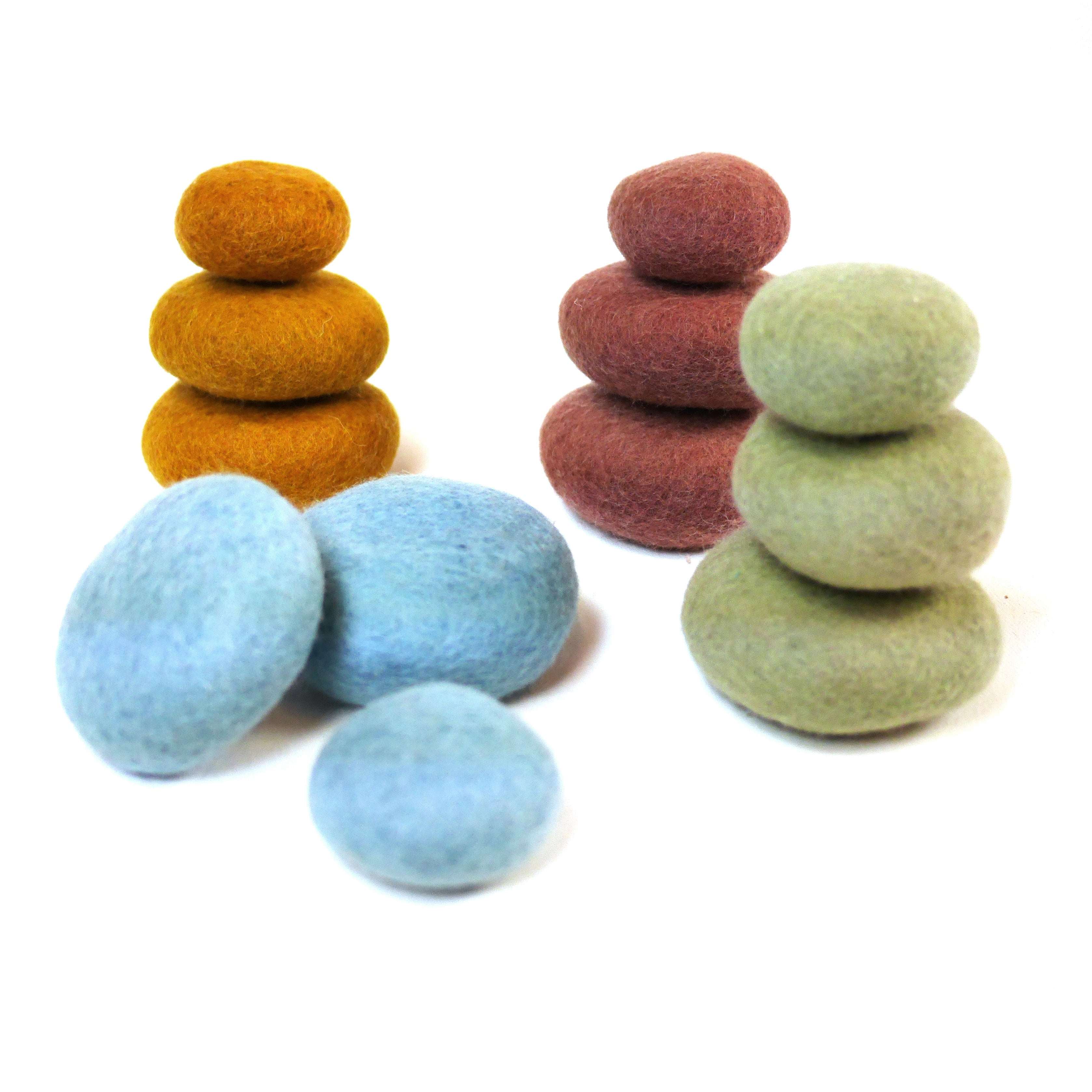Twelve felted wool stacking pebbles in sage, blue, brick, and golden brown arranged in stacks and loose parts.