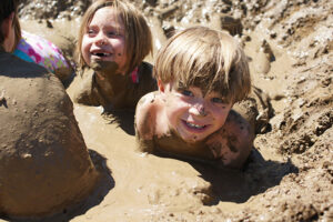 Smiling children laying in the mud