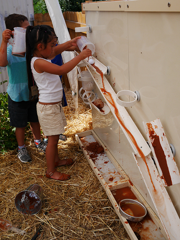 Children pouring slurry down ramps on the Kodo Magnet Wall
